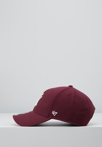 Burgunderfarget baseballcaps med buet brem, brodert hvit logo på fronten, og '24/7' detaljer på siden. Laget av teksturert stoff.