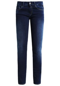 Pantalones vaqueros skinny de mezclilla azul oscuro con diseño de cinco bolsillos, cierre de botón y costuras en contraste. Textura suave y ajuste ceñido.