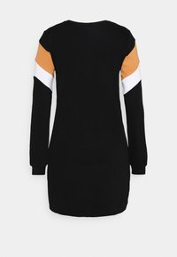 Robe noire à manches longues avec des accents angulaires en blocs de couleur orange et blanche sur les manches. Tissu doux et lisse avec un col rond.