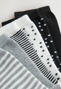 Viis paari puuvillaseid sokke. Värvivariandid hõlmavad halli, valget ja musta, triipude ja täppide mustritega.