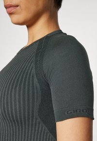 Czarny dopasowany t-shirt z krótkim rękawem, z teksturowanym, prążkowanym wzorem i akcentami z logo na rękawie. Gładki materiał i sportowy krój.