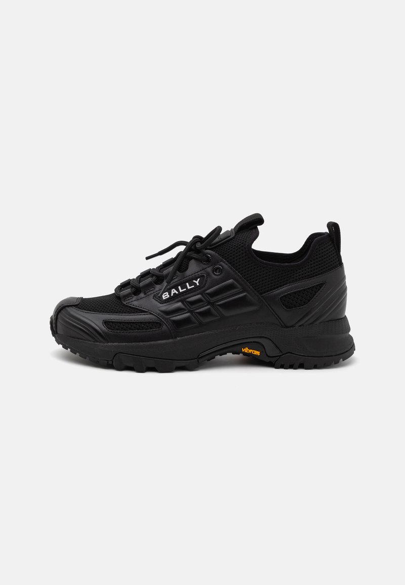 Scarpe da ginnastica nere realizzate con un mix di materiali sintetici testurizzati e rete. Presentano una suola robusta, un sistema di allacciatura e un dettaglio del logo prominente.