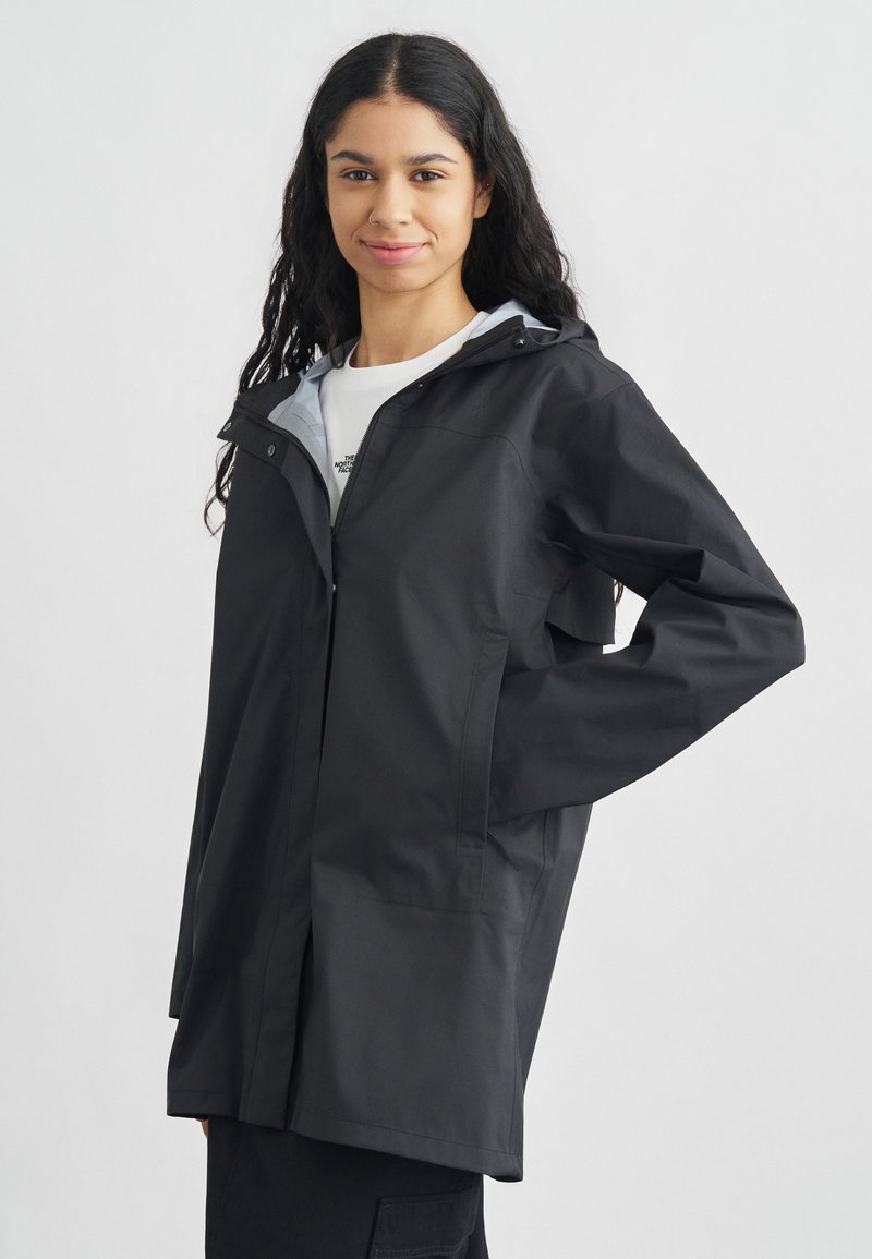 Μαύρο αδιάβροχο μπουφάν με κουκούλα, με μπροστινό φερμουάρ και πλαϊνές τσέπες. Η εσωτερική πλευρά είναι ανοιχτό γκρι με λεία υφή.