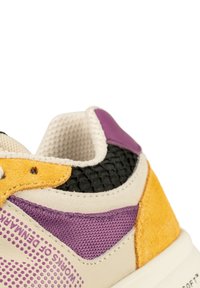 Baskets multicolores avec une tige synthétique crème ornée d'accents violets, jaunes et noirs, de superpositions texturées et d'un branding prononcé.