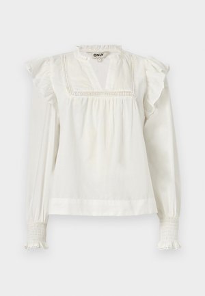 Valge puuvillane pluus kõrge kaelusega, volangidega varrukate ja ees kaunistava pitsilise äärisega. Omab kitsaid mansette, millel on kortsuline disain.