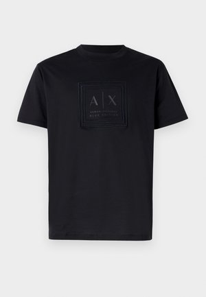 Černé bavlněné tričko s obdélníkovou nášivkou loga s nápisem "A|X" a "Armani Exchange Blue Edition" v tmavých barvách na přední straně. Design s kulatým výstřihem.