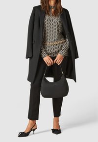 Černý kabát, vzorovaný top v černé a bílé, černé kalhoty, černá kabelka a černé boty s puntíky a mašličkami. Zlatý detail na pásku.