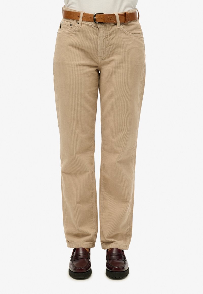 Pantalon beige en velours côtelé coupe droite avec une ceinture en cuir marron, associé à des mocassins marron foncé, montré de la taille aux pieds.