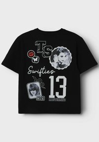 Čierne tričko s krátkym rukávom s rôznymi grafikami: veľké číslo "13," "TS," "Swifties," a obrázky motýľa a tvárí v kontrastných farbách.