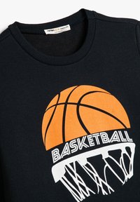 Czarny sweatshirt z dużą pomarańczową grafiką koszykówki nad napisem "BASKETBALL" oraz białym wzorem siatki kosza.