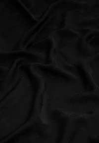 Tissu noir avec une texture lisse et mate, présentant des motifs tonaux subtils. Le matériau semble froissé, mettant en valeur des plis et des ombres.