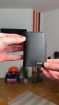 Black leather wallet with a textured surface, featuring a white "BOSS" logo, compact design, and neat stitching along the edges.