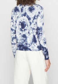 Bomullströja med batikmönster i marinblått och vitt, med ribbad nederkant och muddar, med cirkulära mönster över hela bakstycket.