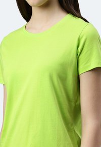 T-shirt a maniche corte realizzato in cotone liscio di un vivace verde lime. Presenta un classico collo a giro e una vestibilità comoda.