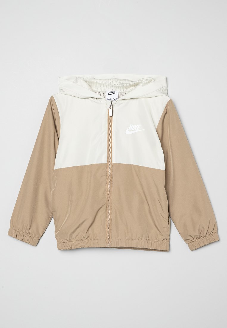 Veste à capuche Nike avec une partie supérieure blanche et une partie inférieure beige. Présente des poignets élastiques et une fermeture éclair à l'avant. Le matériau semble lisse.