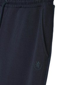 Ciemnoniebieskie dresy z miękkiego materiału, z elastycznym pasem w talii, bocznymi kieszeniami oraz subtelnym logo na lewej udzie.