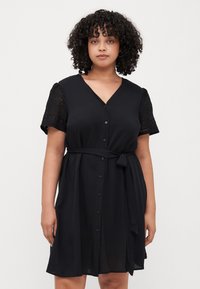 Black dress with a V-neck, short lace sleeves, and a tied waist. It features a button-down front and a flowy design.