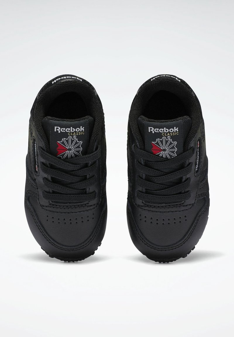 Baskets noires avec dessus en cuir, design à lacets, boîte à orteils perforée et logo sur la languette. Présentent des accents texturés et une semelle extérieure en caoutchouc.