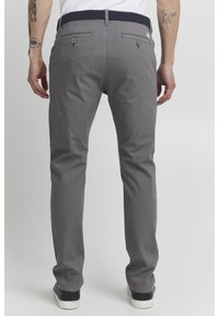Pantalones de algodón gris tipo chambray con un corte recto, que cuentan con bolsillos traseros y un cinturón tejido azul marino texturizado. Zapatillas negras completan el look.