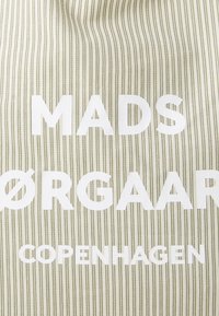 Borsa in tela con strisce verticali verdi e bianche. Grande testo bianco che mostra "MADS ØRGAARD COPENHAGEN" in modo prominente. Texture liscia.