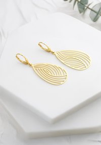 Guldpläterade örhängen med en droppeform som har lager av kurviga linjer. De hänger från fjädrande låsspärrar på en vit hexagonal bas.