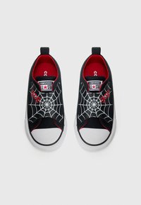 Melnas auduma slip-on kurpes ar baltu zirnekļu tīkla dizainu, sarkanu odere un gumijas purngaliem. Iezīmēta ar logotipu uz mēles un astes cilpu.