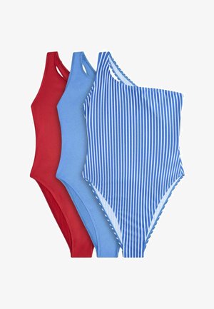 Tre costumi da bagno interi da donna in rosso, azzurro chiaro tinta unita e blu con righe verticali bianche, disposti sovrapposti su uno sfondo bianco.