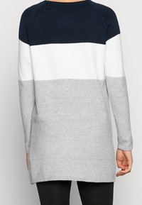 Pull en tricot avec des rayures horizontales bleu marine, blanches et grises. Manches longues, ourlet arrondi et texture douce. Longueur dépassant les hanches.