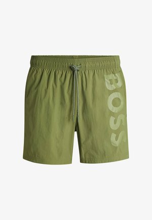 Olive green swim shorts made of lightweight fabric, featuring an elastic waistband with drawstring and a large "BOSS" logo in light green on the side.