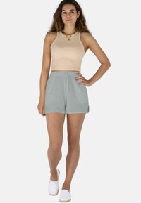 Hellbeige gerippter Cropped-Tanktop, kombiniert mit weichen, hellgrauen Shorts. Die Shorts haben einen elastischen Bund und seitliche Taschen und bieten einen lockeren Sitz.