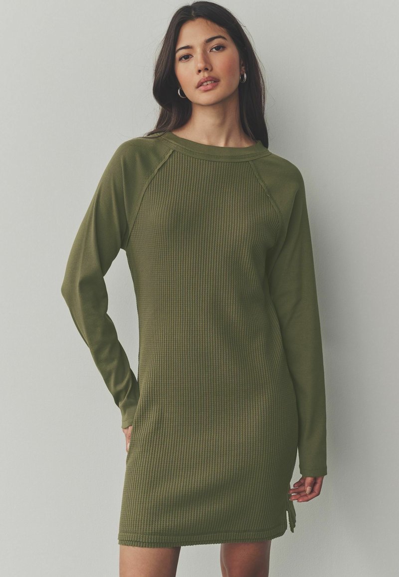 Robe longue à manches longues côtelée en vert olive, dotée d'un col rond, de fentes sur les côtés et d'une coupe décontractée pour le confort et la liberté de mouvement.
