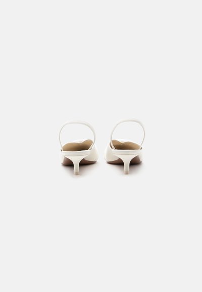 Ζευγάρι λευκά πέδιλα τύπου slingback με μικρό τακούνι, σε λευκό φόντο, από πίσω.