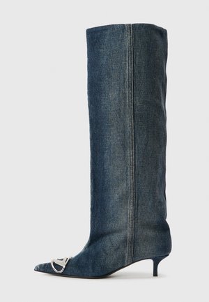 Stivale alto fino al ginocchio in denim con punta a punta, dettagli in metallo argentato, tacco a gattino sottile e finitura liscia e texturizzata.