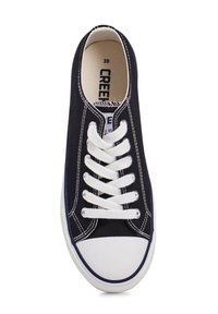 Zapatilla de lona negra con cordones blancos, costuras en contraste, suela de goma y punta redondeada. Interior marcado con etiqueta de tamaño.