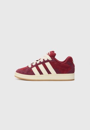 Niski bordowy zamszowy sneaker z białymi sznurowadłami, trzema białymi paskami po bokach i kremową podeszwą.
