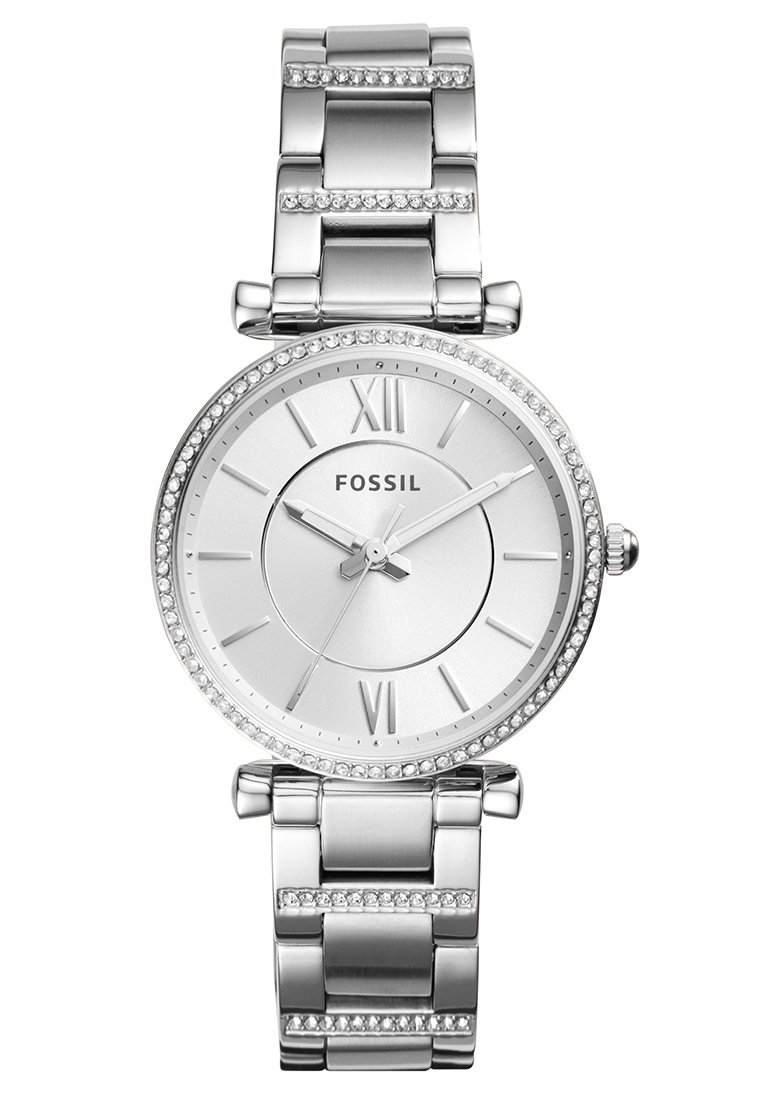 Montre fossile en argent avec un cadran rond, des chiffres romains et des accents en cristal. Dispose d'un bracelet en métal poli avec un fermoir assorti.
