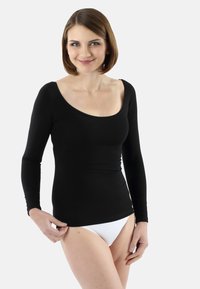 Black long-sleeve top with a scoop neckline, fitted design, and smooth texture, paired with white underwear. Model standing with hand on hem.