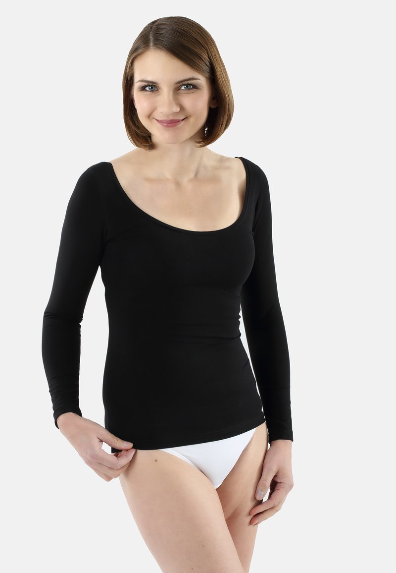 Black long-sleeve top with a scoop neckline, fitted design, and smooth texture, paired with white underwear. Model standing with hand on hem.