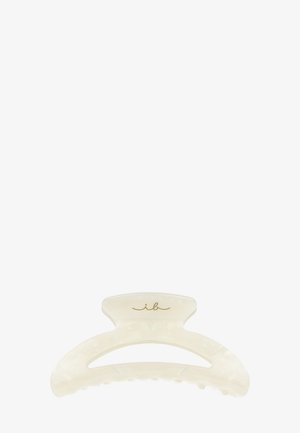 Off-white plastik hårklemme med buet top og guld skriftlogo "ib" centreret på toppen.