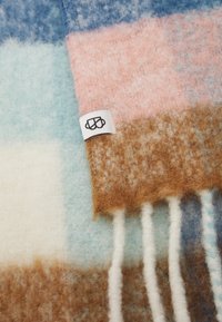 Wolldecke mit einem Karomuster in Blau-, Pink-, Creme- und Brauntönen. Besitzt eine weiche Textur und weiße Fransen an einer Kante.