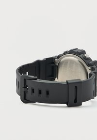 Μαύρο ψηφιακό ρολόι με λουράκι σιλικόνης και πίσω μέρος από ανοξείδωτο ατσάλι. Διαθέτει στρογγυλό καντράν και ασφαλές κούμπωμα.