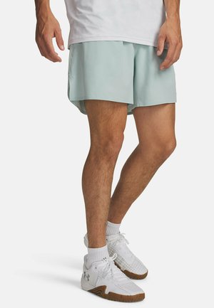 Hellblaue Sportsshorts aus schnell trocknendem Stoff, mit lockerem Schnitt, Seitenschlitzen, kombiniert mit weißen, strukturierten Schuhen und Socken.