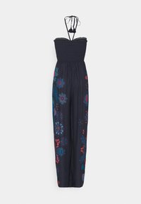 Marinblå jumpsuit med en smockad överdel och tunna axelremmar, med färgglad blomsterbroderi på benen i röd, blå och turkos.