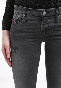 Vaqueros gris denim de corte ajustado, con detalles de roturas, diseño clásico de cinco bolsillos y efecto de lavado claro en la tela.