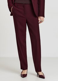 Pantalon bordeaux à fines rayures, coupe ajustée, confectionné dans un tissu texturé. Porté avec un haut uni marron foncé et des talons assortis bordeaux.