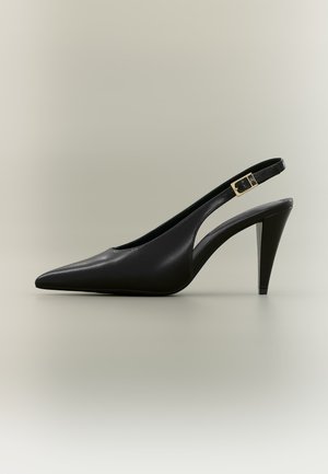 Zapato de tacón alto tipo slingback de cuero negro con punta puntiaguda, hebilla dorada y tacón afilado sobre un fondo neutro.