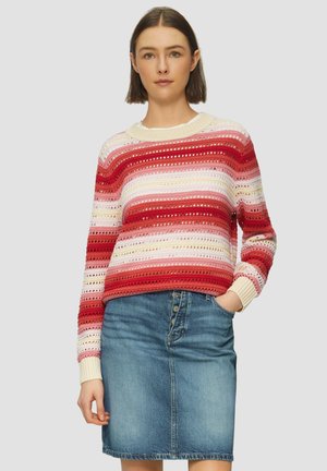 Rood en roze gestreepte gebreide trui met opengewerkte ontwerpen, gecombineerd met een lichtblauwe denimrok met knopen aan de voorkant en zakken.