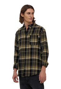 Camicia in flanella a button-up con motivo a quadri neri, oliva e bianchi; presenta una tasca sul petto e maniche arrotolate. Tessuto morbido.