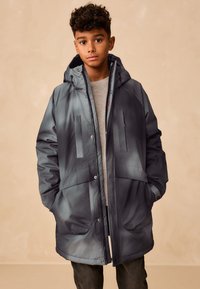 Doudoune gris foncé avec capuche, dotée de deux poches avant, d'une fermeture éclair et d'une finition lisse et réfléchissante. Design intérieur simple.