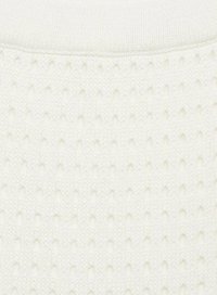 Tissu tricoté blanc présentant un motif texturé avec de petites formes de diamants surélevées. Apparence douce avec un éclat subtil.